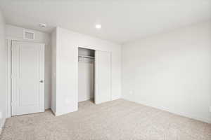Unfurnished bedroom featuring light colored carpet, a closet, and recessed lighting