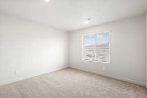 Empty room with light carpet and recessed lighting