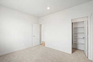 Unfurnished bedroom featuring a spacious closet, light colored carpet, and recessed lighting