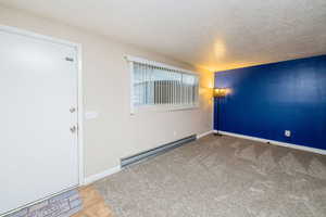 Spare room featuring a baseboard heating unit, a textured ceiling, and carpet