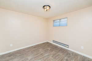 Spare room with wood finished floors, a textured ceiling, and a baseboard radiator