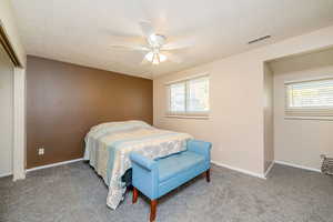 Carpeted bedroom featuring a textured ceiling and a ceiling fan