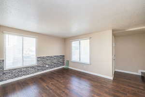 Unfurnished room featuring a textured ceiling and dark wood-style floors