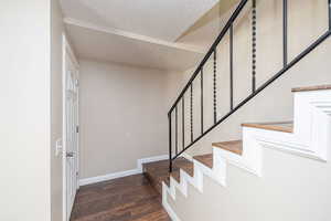 Stairs with a textured ceiling and wood finished floors