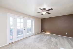 Empty room featuring french doors, a textured ceiling, light carpet, and a ceiling fan