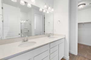 Bathroom with a stall shower, double vanity, a spacious closet, and light wood-style floors