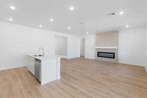 Kitchen featuring recessed lighting, light wood-style flooring, white cabinets, an island with sink, and open floor plan