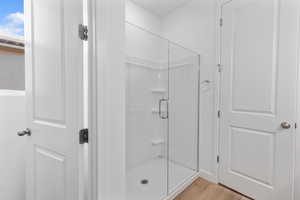 Full bath featuring light wood-style floors and a shower stall