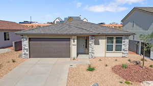 View of front of house featuring stone siding, stucco siding, concrete driveway, and a garage