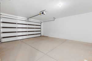 Garage featuring baseboards and a garage door opener