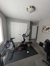 Exercise area with a textured ceiling and dark colored carpet