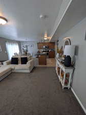 Living area with a textured ceiling, light colored carpet, a chandelier, and light tile patterned floors