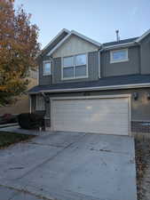 View of front of house with an attached garage, concrete driveway, stucco siding, and board and batten siding