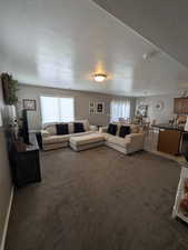 Carpeted living area featuring a textured ceiling and a chandelier