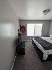 Carpeted bedroom featuring a textured ceiling and baseboards