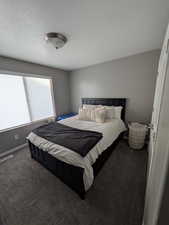 Carpeted bedroom featuring a textured ceiling and baseboards