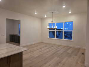Unfurnished dining area with light wood-style floors and a chandelier
