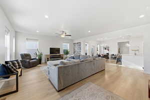 Living room with a ceiling fan, recessed lighting, light wood-type flooring, and a chandelier