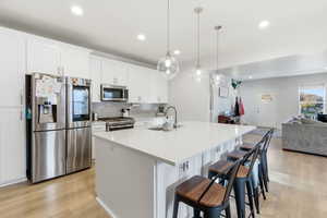 Kitchen with stainless steel appliances, quartz oversized island, pendant lights and open floorplan.
