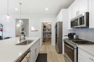 Kitchen with stainless steel appliances, quartz oversized island, pendant lights and open floorplan.