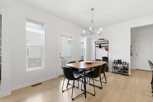 Dining space with light wood-style floors and a chandelier