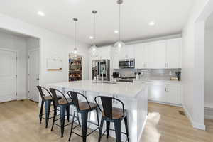 Kitchen with stainless steel appliances, quartz oversized island, pendant lights and open floorplan.