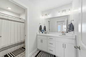 Full bath featuring curtained shower and double vanity