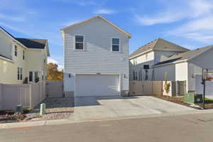 View of front of home with a gate, concrete driveway, and an attached garage