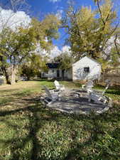 View of green lawn featuring a patio and an outdoor fire pit