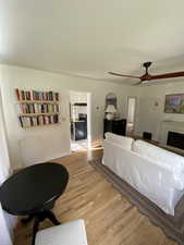 Bedroom featuring light wood-type flooring, a fireplace, and ceiling fan