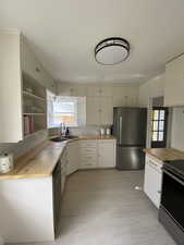 Kitchen with butcher block counters, tasteful backsplash, stainless steel appliances, and healthy amount of natural light