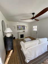 Living room featuring wood finished floors, a fireplace, and a ceiling fan