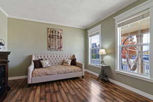 Living area with ornamental molding and wood finished floors