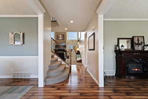 Staircase with wood finished floors, a fireplace, ornamental molding, and recessed lighting