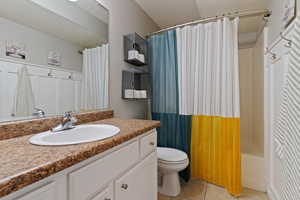 Full bathroom featuring vanity, light tile patterned floors, and shower / bath combo with shower curtain