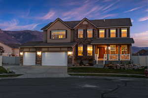 Traditional-style home with a mountain view, a tiled roof, concrete driveway, stone siding, and covered porch
