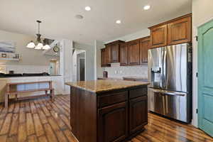 Kitchen featuring stainless steel fridge, dark wood-style flooring, tasteful backsplash, hanging light fixtures, and recessed lighting