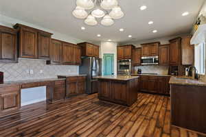 Kitchen featuring light stone counters, a kitchen island, stainless steel appliances, decorative backsplash, and recessed lighting