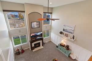 Living area featuring a decorative wall, a fireplace, a high ceiling, carpet flooring, and wainscoting