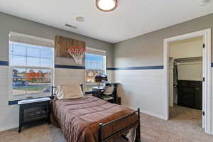 Bedroom with light carpet and a walk in closet