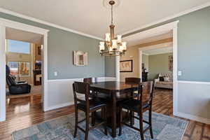 Dining space featuring crown molding, dark wood-style flooring, and a chandelier