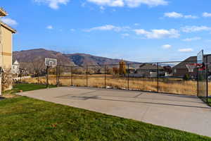View of basketball court with basketball hoop, a mountain view, and a residential view