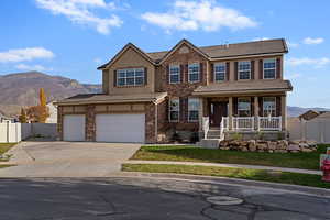 Traditional-style home featuring a mountain view, stone siding, driveway, stucco siding, and a tile roof