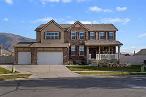 View of front facade with a tile roof, stone siding, concrete driveway, covered porch, and stucco siding