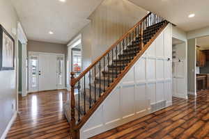 Foyer featuring stairs, dark wood finished floors, and recessed lighting