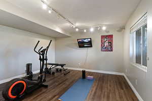 Exercise room featuring dark wood-type flooring and rail lighting