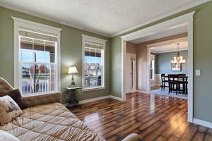 Living area featuring crown molding, wood-type flooring, and a chandelier