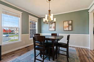 Dining room with ornamental molding, wood finished floors, and a chandelier