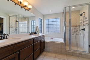 Bathroom with a stall shower, double vanity, light tile patterned flooring, a garden tub, and a walk in closet