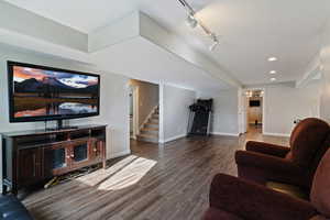 Living area featuring wood finished floors, stairs, rail lighting, and recessed lighting